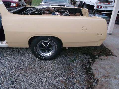1971 Ford Ranchero - A tan 1970 Ford Ranchero is shown from the side, with its bed filled with parts and other vehicles in the background.