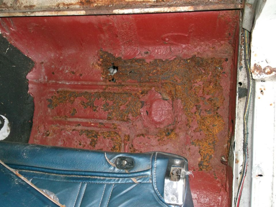 rusted red floor pan with blue seat trim visible