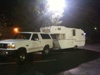 1963 Ford Deluxe - A white pickup truck tows a camper trailer in this nighttime photograph.