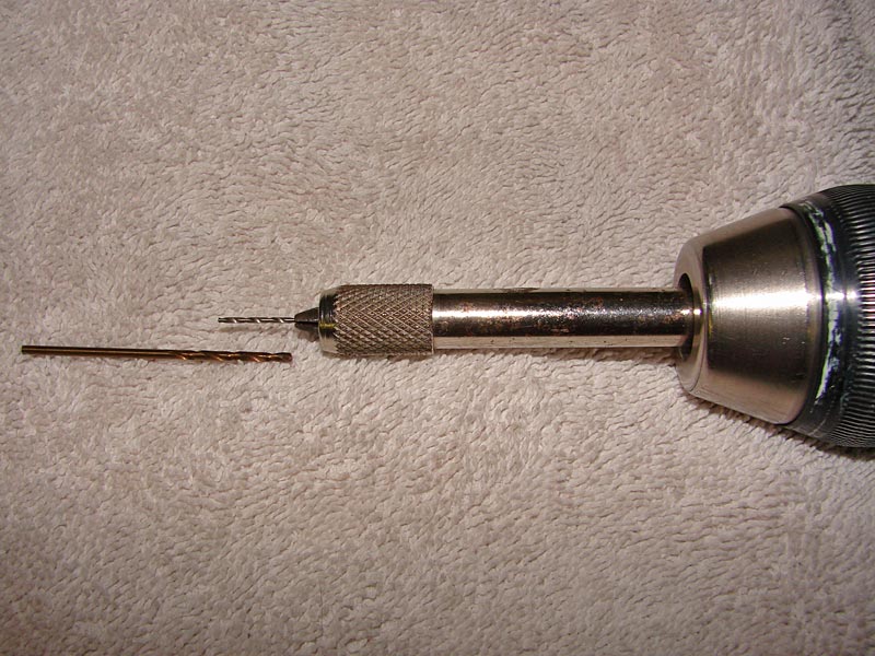 Drill chuck with a small drill bit inserted and another bit lying next to it
