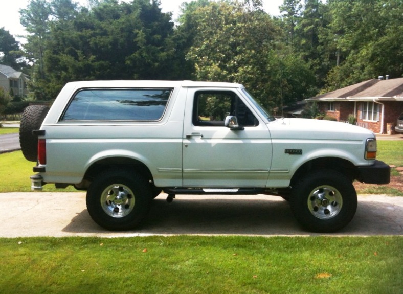 White 1993 Ford Bronco parked on a driveway, side view, with a spare tire mounted on the rear