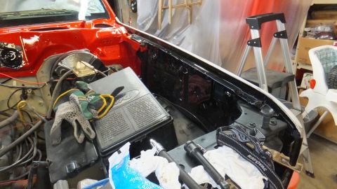 1983 Ford Bronco - The engine bay of a red Ford Bronco is shown during a restoration project, with various parts and tools laid out.