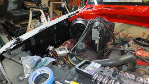 1983 Ford Bronco - Vehicle engine bay in a state of repair, showing the firewall, fan, and engine parts with tools nearby.