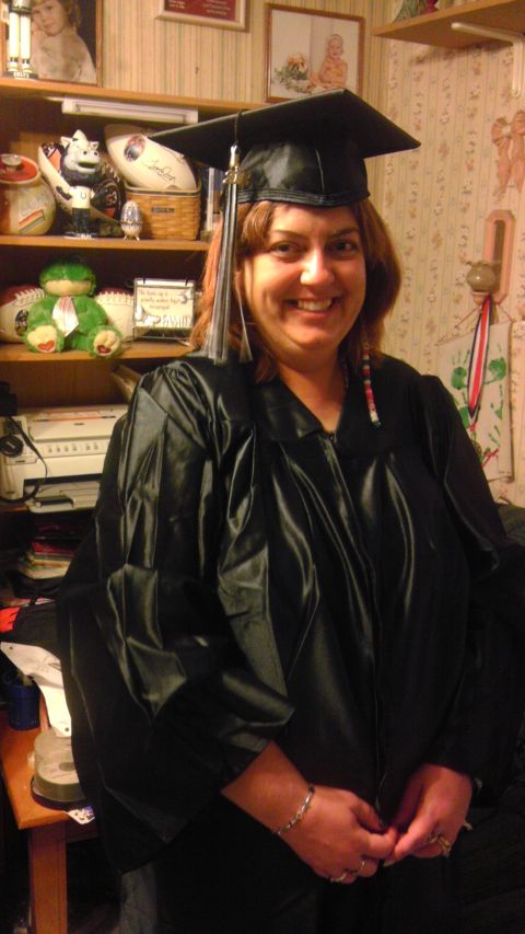 1989 Ford Bronco - A woman poses for a photo in her graduation attire, with shelves filled with various items in the background.