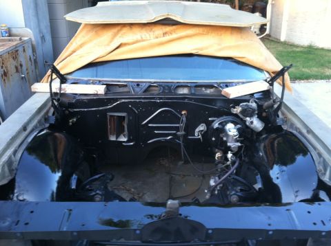 1967 Pontiac Grand Prix - The engine bay of a 1967 Pontiac Grand Prix is visible, with a tarp covering the windshield and hood area.