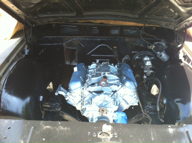 Engine bay with a V8 engine installed. The engine is silver with blue valve covers and a chrome air cleaner