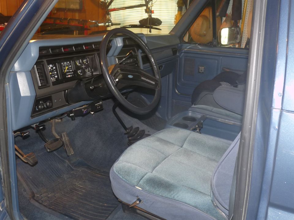 1986 Ford Bronco interior showing blue seats, dashboard, and steering wheel