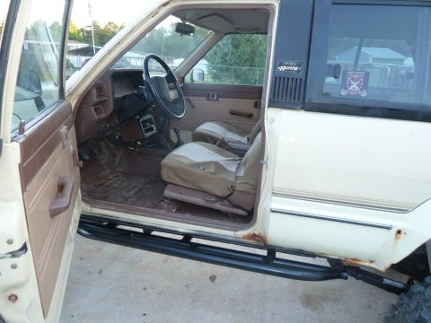 1992 Ford Mustang - The interior of a beige Toyota 4Runner is visible with the driver's door ajar, revealing tan seats and floor mats.