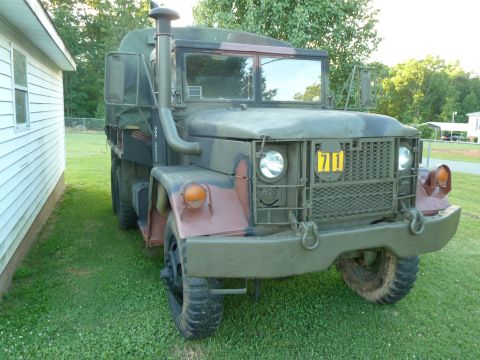 1992 Ford Mustang - This military truck, marked with a yellow '71' badge, is seen parked on a grassy lawn next to a white building.