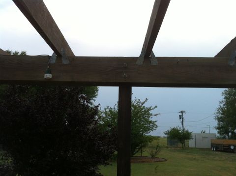 1994 Ford Bronco - View through a wooden pergola structure showing trees, a trailer, and utility pole in the background.