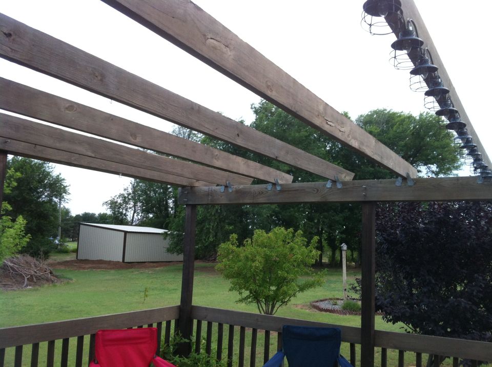 Backyard view from a deck, showing a shed, trees, and a pergola with lights