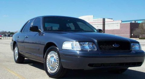1998 Ford Crown Victoria - A 1998 Ford Crown Victoria sedan is shown from the front three-quarter angle under a clear blue sky.