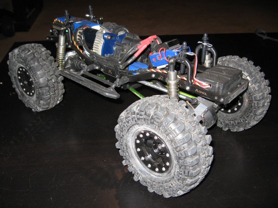 RC rock crawler with large tires, exposed electronics, and blue body panels