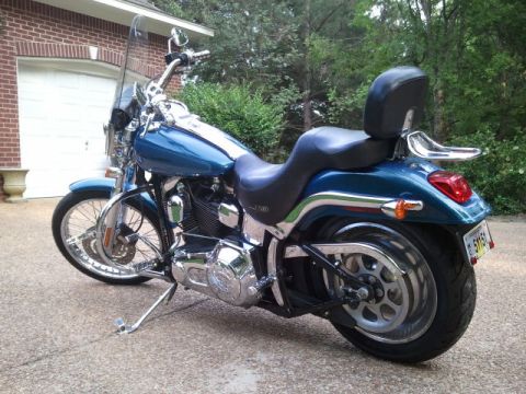 1967 Ford Mustang - A blue Harley Davidson motorcycle is parked on a paved surface in front of a residential garage.