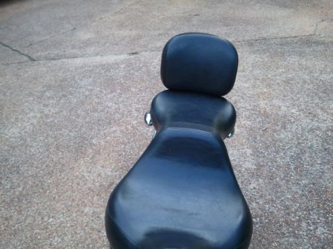 1967 Ford Mustang - A black motorcycle seat with a backrest is viewed from above, resting on a concrete surface.