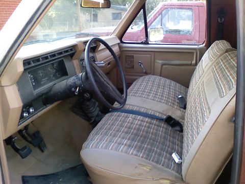 1981 Ford Bronco - Interior of a pickup truck, with a second vehicle visible outside the passenger window.