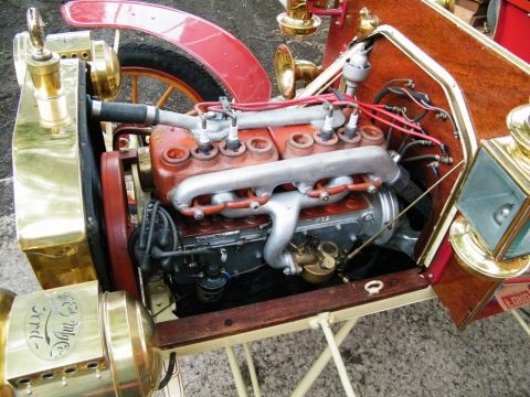 1906 Ford Model T - Close-up of the engine bay of an early automobile, a brass radiator with 'Ford' script and a wooden dashboard.