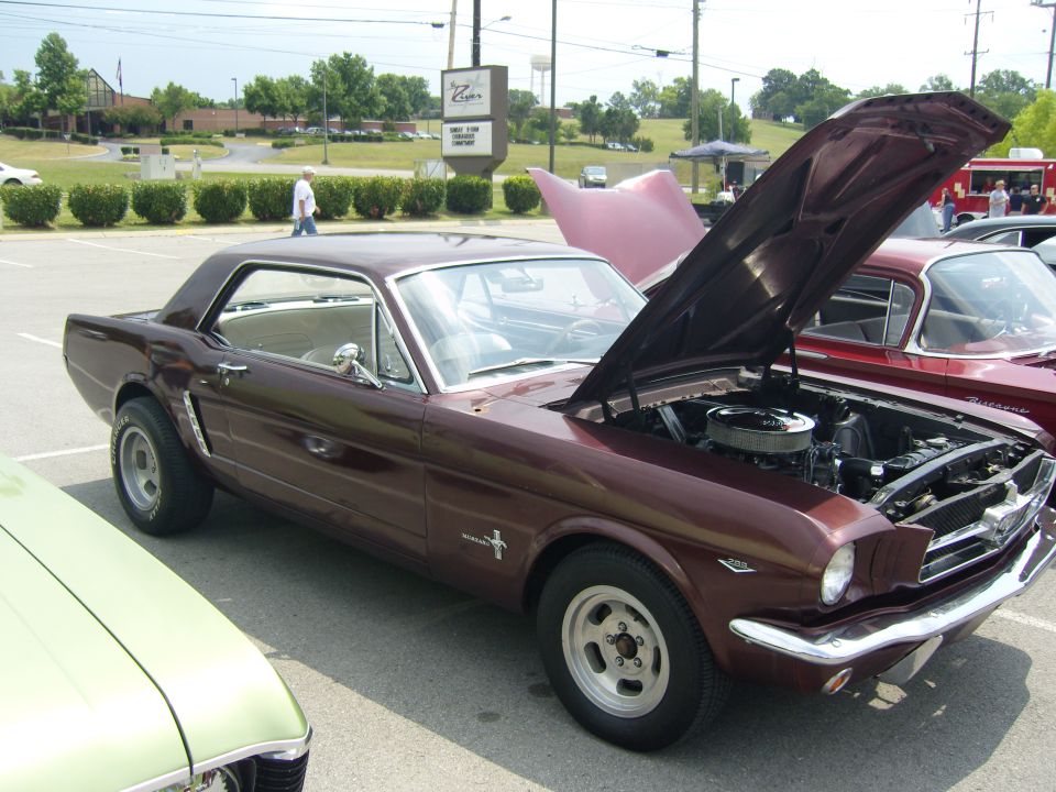 Maroon 1965 Ford Mustang coupe with hood open, parked next to a green car and a red car