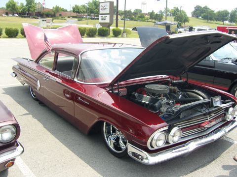 2007 Ford Mustang - A classic maroon 1959 Chevrolet Bel Air is displayed with its hood and trunk open at an outdoor car show.