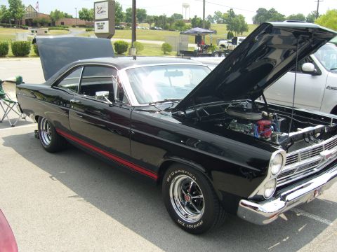2007 Ford Mustang - A black 1967 Ford Fairlane coupe is displayed with its hood open, revealing the engine. The car features a red stripe along its side.