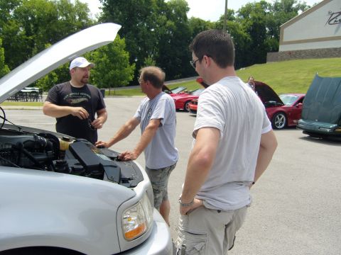 2007 Ford Mustang - Three men examine the engine of a silver pickup truck at an outdoor car show.