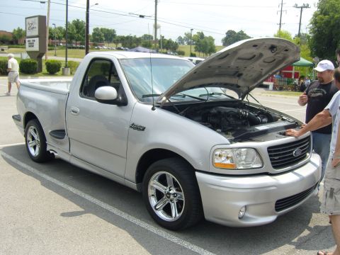 2007 Ford Mustang - A silver pickup truck is parked with its hood open, revealing the engine compartment.
