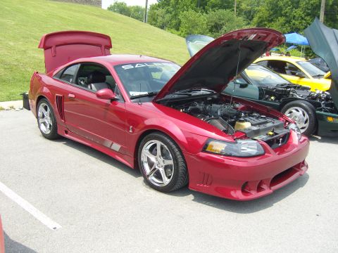2007 Ford Mustang - Red Saleen Mustang at car show, hood and trunk open, other vehicles visible.