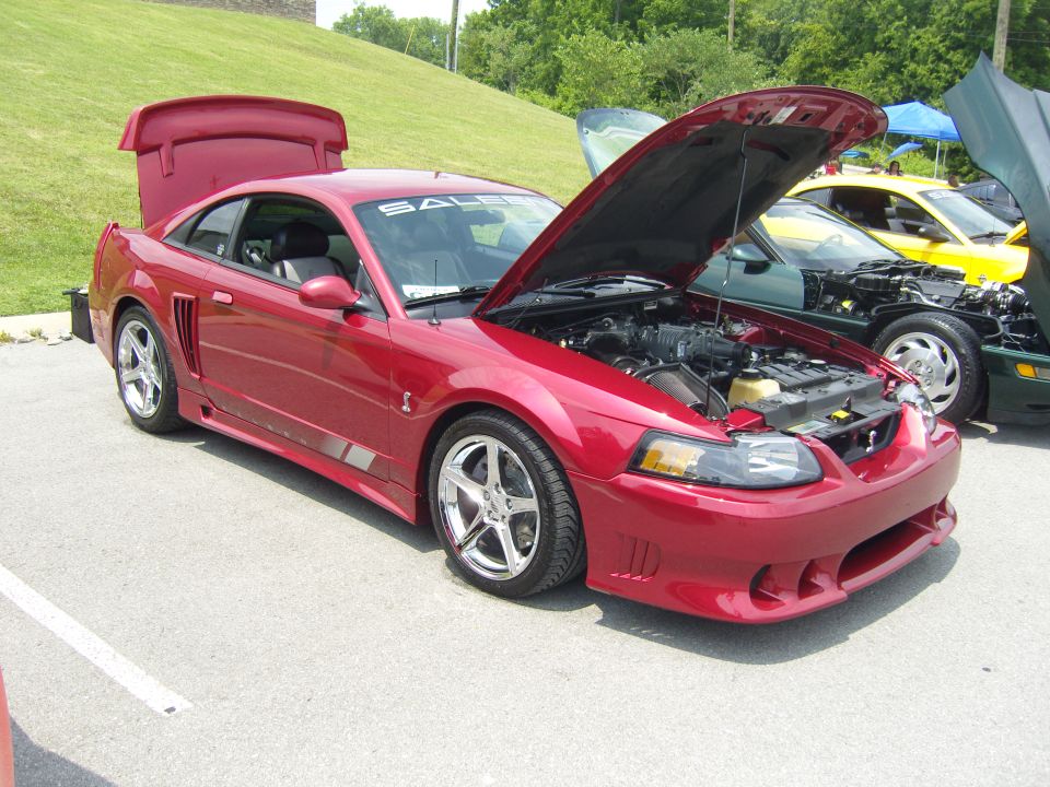 Red Saleen Mustang with hood and trunk open, parked next to other cars