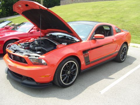 2007 Ford Mustang - A red Ford Mustang Boss 302 is parked with its hood open, next to another red car.