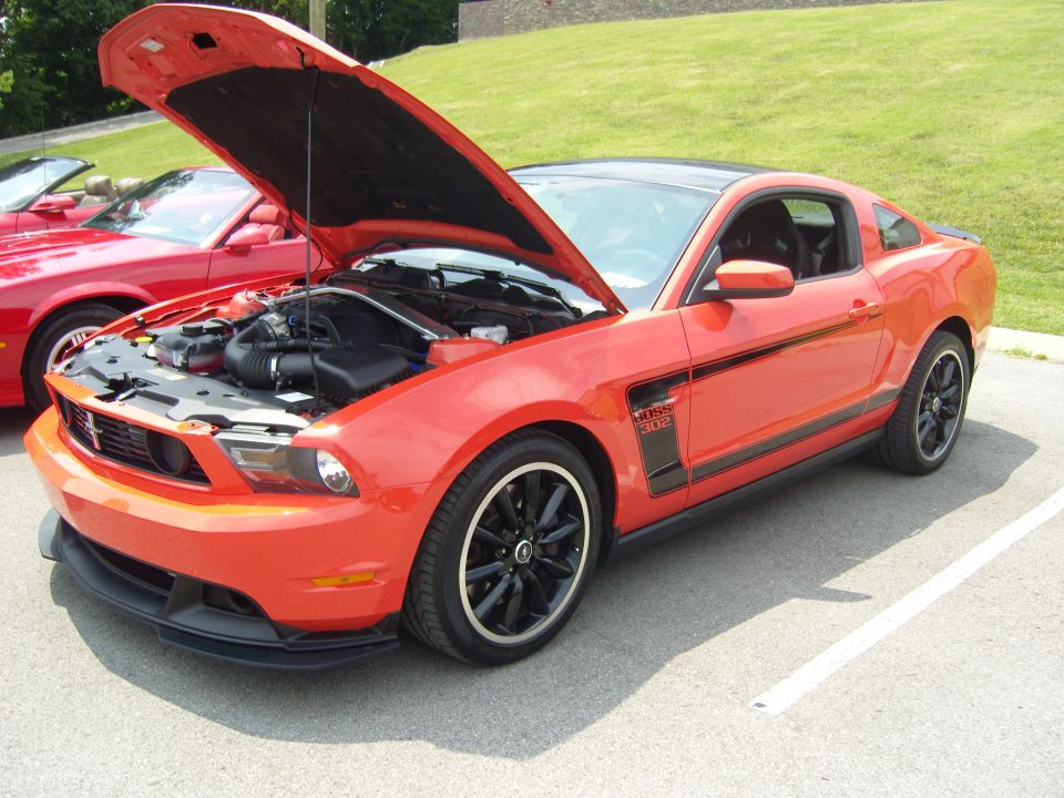 Orange Mustang Boss 302 with hood open, parked next to a red convertible