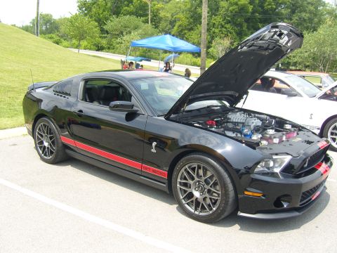 2007 Ford Mustang - A black 2007 Ford Mustang Shelby GT500 is parked with its hood open, displaying the engine and supercharger.