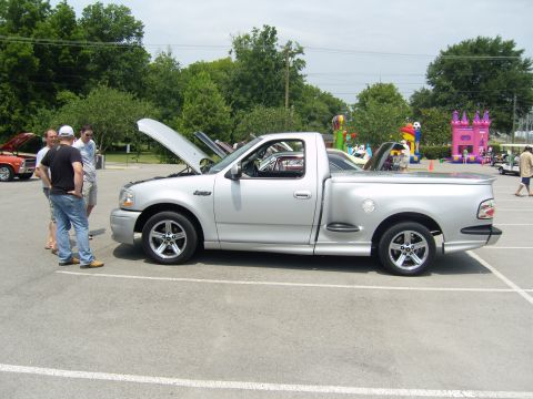2007 Ford Mustang - A silver pickup truck is parked with its hood open at an outdoor event.