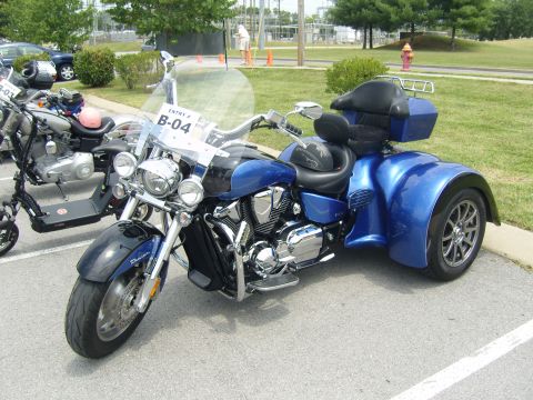 2007 Ford Mustang - A blue trike motorcycle is parked on asphalt with a scooter nearby.
