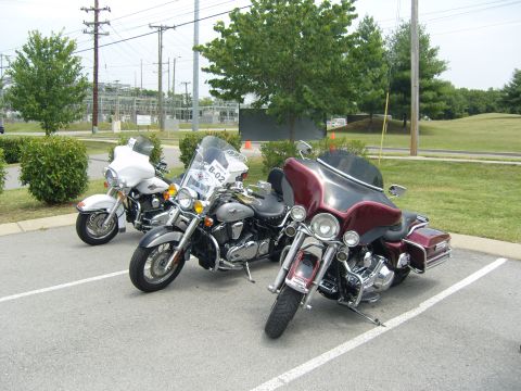 2007 Ford Mustang - Three motorcycles are parked in a lot with power lines and an industrial building in the background.