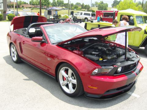 2007 Ford Mustang - A red convertible Mustang GT is parked with its hood open, displaying the engine bay.