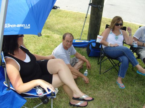 2007 Ford Mustang - People enjoy a sunny day outdoors, seated in chairs under a large blue umbrella.