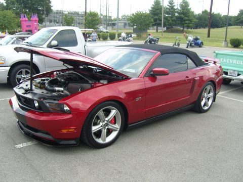 2007 Ford Mustang - A red convertible sports car is parked with its hood open, revealing the engine compartment.