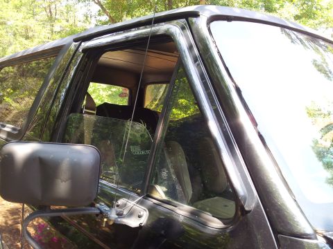 1986 Ford Bronco - The interior of a black SUV is visible through the side window, which has a decal on it.