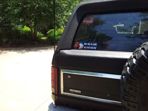1986 Ford Bronco - Rear view of a black Ford Bronco with a humorous sticker on the window and "SIZE MATTERS" on the tailgate.