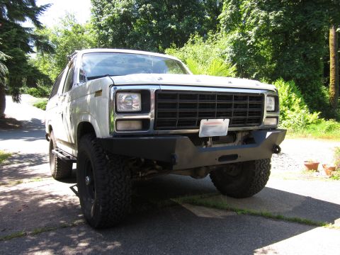 1989 Ford Bronco - This white Ford Bronco, likely from the early 1980s, is equipped with a custom bumper and large tires.