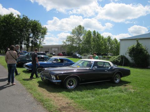 1991 Ford LTD Crown Victoria - A classic car show with several vehicles on display under a partly cloudy sky.