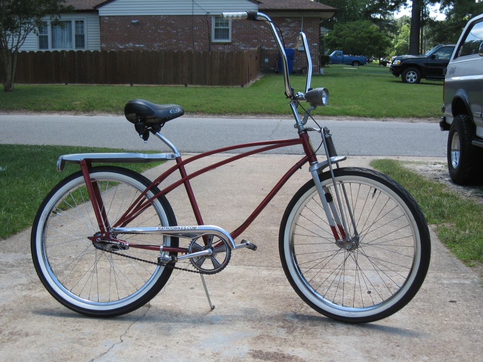 Maroon cruiser bicycle with chrome handlebars and rack, parked on concrete