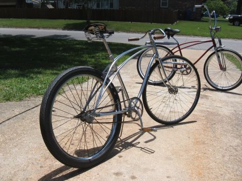 1994 Ford Bronco - Two cruiser bicycles, one chrome and one red, are parked on a concrete surface on a sunny day.