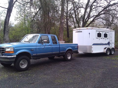 1992 Ford F-150 - Blue 1992 Ford F-150 pickup truck is shown towing a white trailer.