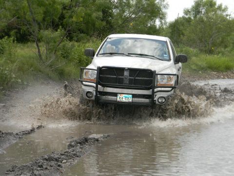 1989 Ford Bronco - This truck is kicking up a lot of mud as it drives through a watery, muddy path.