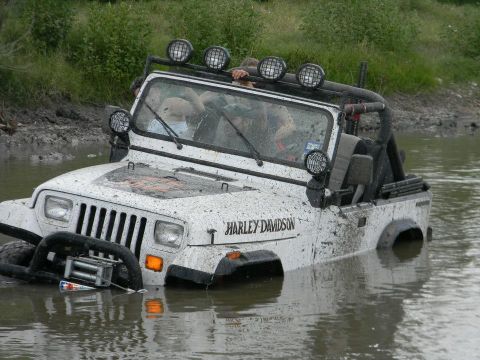 1989 Ford Bronco - A white Jeep with a Harley-Davidson decal is stuck in the water, with only the top half visible.