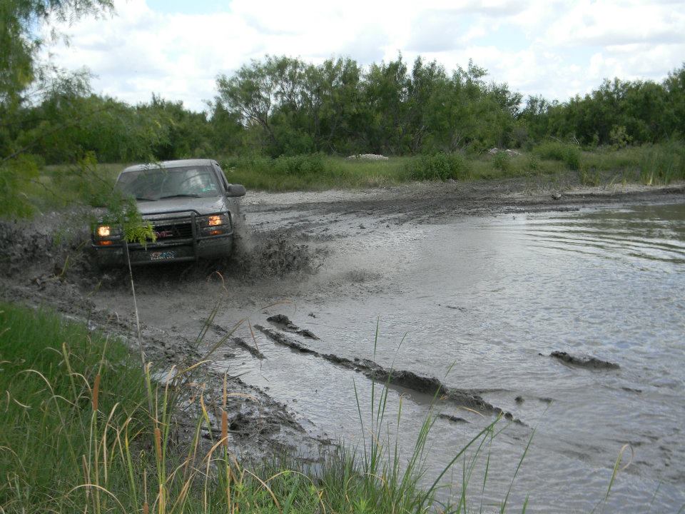 GMC pickup truck splashing through a muddy puddle off-road