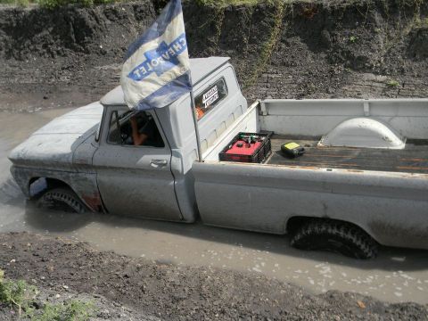 1989 Ford Bronco - This pickup truck is stuck deep in mud, with a Chevrolet flag flying from the cab.