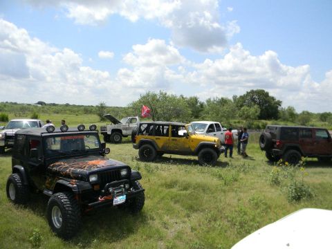1989 Ford Bronco - Multiple off-road vehicles are gathered in an open field on a sunny day.