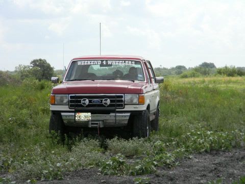 1989 Ford Bronco - This Ford truck appears to be from the late 1980s, not a 1989 model, and is parked in a muddy, grassy area.